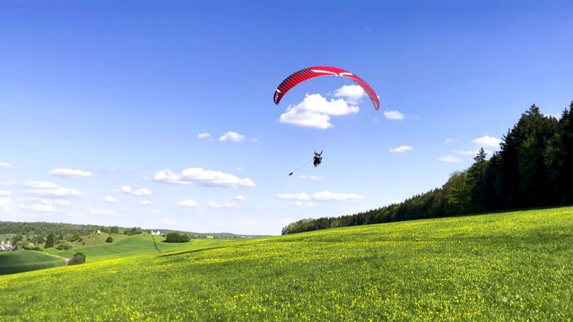 Weite grüne Wiesen und sanfte Hügel unter blauem Himmel.